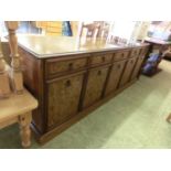 A modern bur walnut and walnut dresser base, three drawers over cupboard doors on plinth base