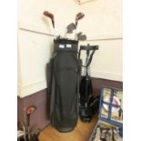 A black canvas golf bag with a selection of golf clubs and a trolley