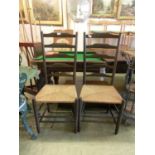 A pair of stained elm ladder back chairs with rush seat