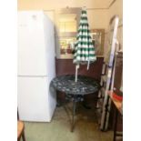 A black painted aluminium garden table with a green and white striped parasol