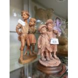 A carved wooden model of young boy and girl together with a plaster model of two young boys