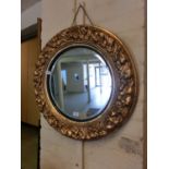 An ornate gilt framed circular bevel glass wall mirror