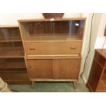 A mid-20th century bookcase cabinet having a pair of glazed sliding doors to top with pull-down flap