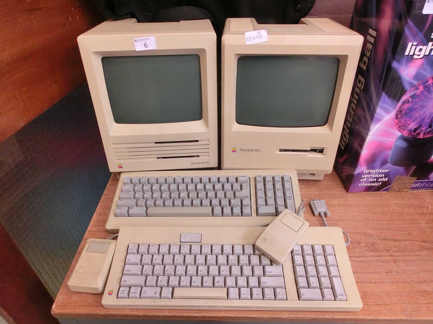 An Apple Macintosh SE computer, along with an Apple Macintosh Plus computer, both with keyboards and
