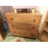 A mid-20th century chest of three drawers with bun handles