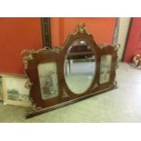 An early 20th century walnut and parcel gilt over mantle mirror, the bevelled oval plate flanked