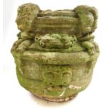 A possible medieval carved stone font, the rim with four masks holding floral swags in their