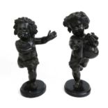 A pair of late 19th century bronze putti, one modelled holding pipes, the other with bird. Mounted