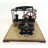 A scale model of a steam powered engine powering a sheet metal press, in glass case, h. 45 cm, w. 54