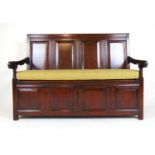 An 18th century oak settle, the four panel back over the lift up seat on a four panel front, with