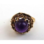 A 9ct gold and amethyst dress ring, the cabochon stone in a modernist design mount. Approx weight