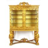 An early 19th century Continental giltwood display cabinet, the cornice with scrolling foliate