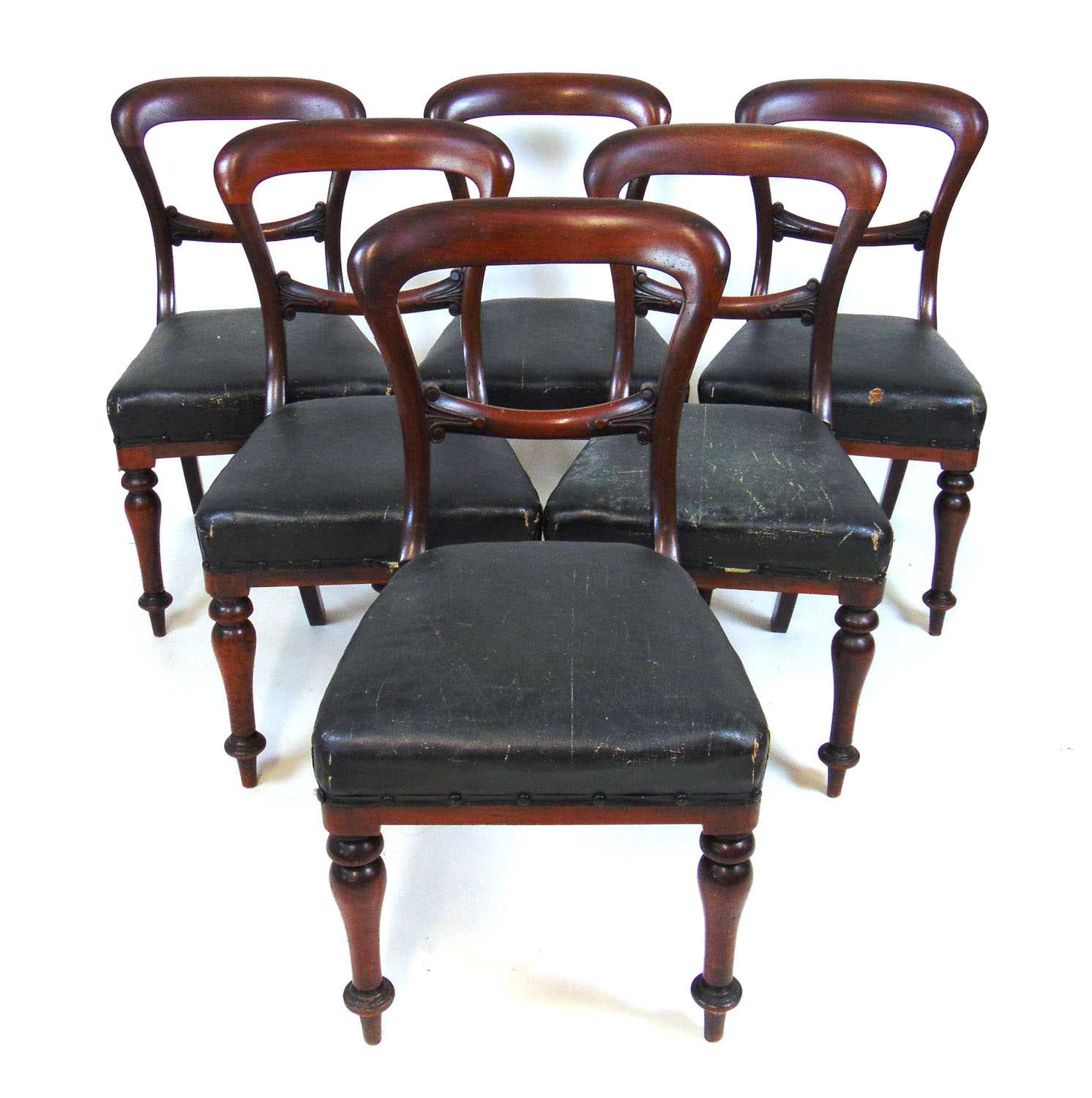 A set of six Victorian mahogany dining chairs, the carved back rail over the black oil skin