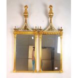 A pair of early 20th century giltwood pier mirrors, the pineapple finial over foliate glass panels