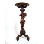 A 19th century walnut Continental jardinière stand, the circular top with carved edge over the putto