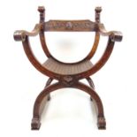 An Italian walnut X-frame armchair, the back support with carved mask finials over slatted seat. h.