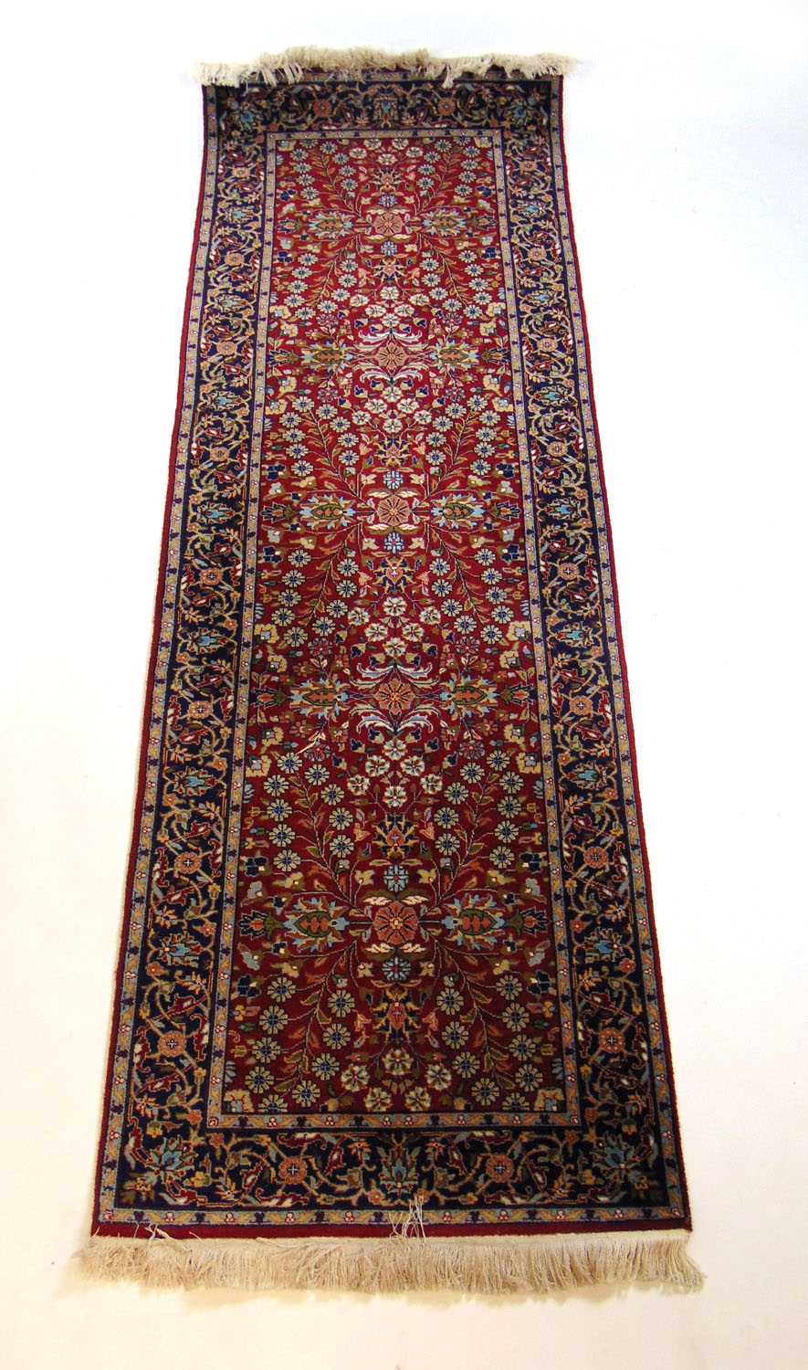 A handwoven Persian runner, the triple line border surrounding the red ground field with floral