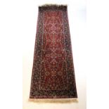 A handwoven Persian runner, the triple line border surrounding the red ground field with floral