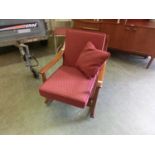 A mid-20th century teak rocking chair upholstered in a red fabric