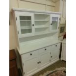 A white modern dresser having open storage flanked by glazed doors to top, the base having three