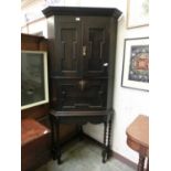 An early 20th century oak floor standing corner cupboard with drop down writing slope