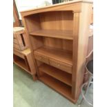 A teak open bookcase with two central drawers