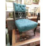 An Edwardian stained beech nursing chair in a green button back fabric