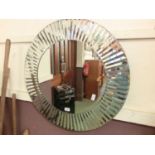 A circular wall mirror with bevelled mirror surround