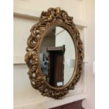 A modern resin oval framed mirror with twin cherubs from E Gomme