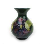 A Moorcroft Clematis pattern baluster vase decorated on a green ground, h. 13 cm