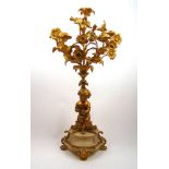 A 19th century French ormolu five branch candelabra, the floral spray over putto column on white