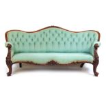 A Victorian walnut settee upholstered in a button back patterned green fabric, the curved back