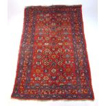 A handwoven Persian rug, the triple line border surrounding the red ground field with floral motif'