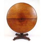 A 19th century Indian rosewood center table, the circular tilt top with floral carved frieze over