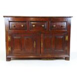 An 18th century and later oak sideboard, the top over three drawers and two field panel cupboard