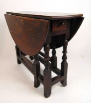 An early 18th century oak and beech drop leaf table, the top supported on a single gate action