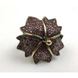 A yellow and white metal ruby set ring of stylized flower form. Marked '18k Silver'. Size M