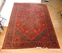 A handwoven Persian style rug, the multi line border surrounding a red ground field with two
