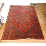 A handwoven Persian style rug, the multi line border surrounding a red ground field with two