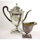 A George III silver coffee pot and matching cream jug, the body with engraved coat of arms and