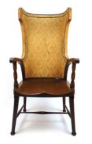 An early 20th century walnut 'porters' chair, the upholstered wing back over open arms with barley