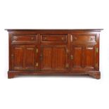 An early 18th century oak dresser base, the moulded top over three drawers and three twin field
