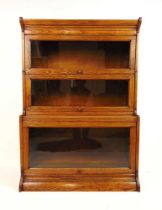 An early 20th century oak sectional bookcase by 'Gunn', the cornice over three glazed section and
