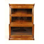 An early 20th century oak sectional bookcase by 'Gunn', the cornice over three glazed section and