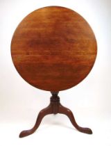 An 18th century oak tilt top tripod table, the circular top on a turned column and three splay legs,