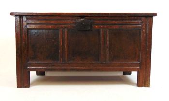 An early 18th century oak coffer, the three panel top lifting to reveal a vacant interior with