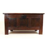 An early 18th century oak coffer, the three panel top lifting to reveal a vacant interior with