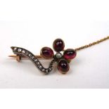 An early 20th century yellow metal, diamond and ruby brooch in the form of a stylized flower, the