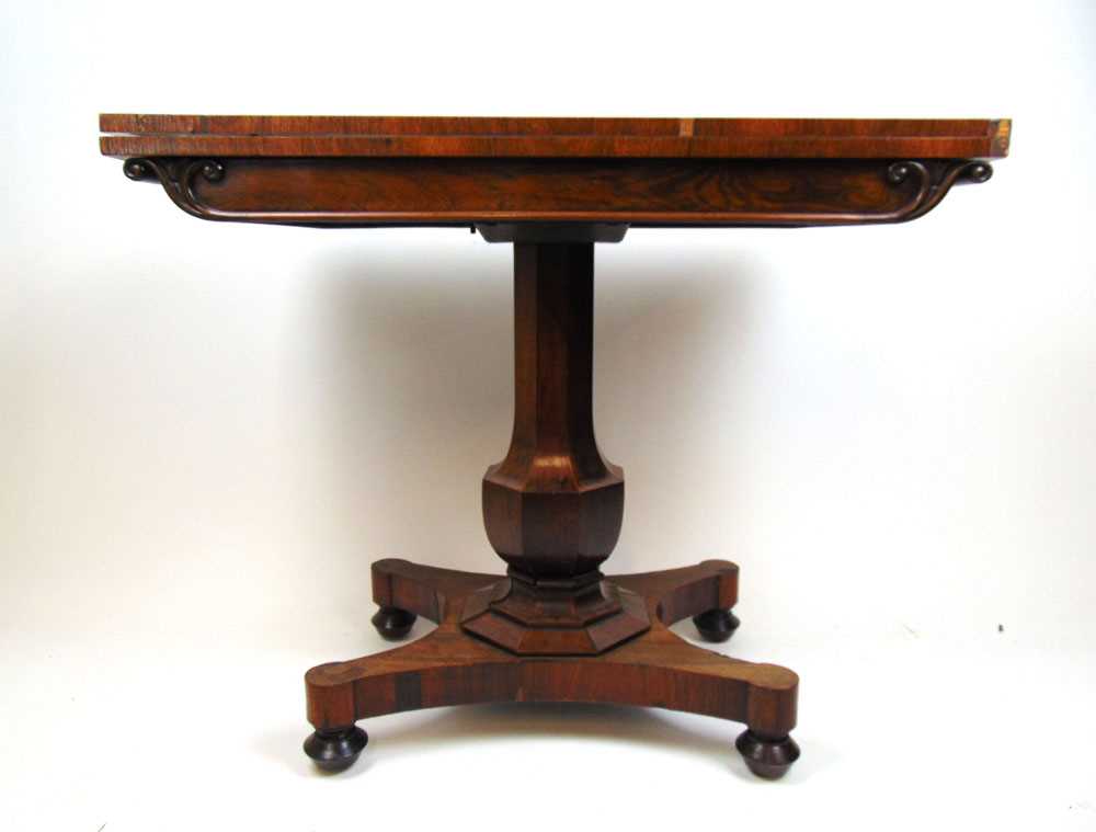 An early Victorian rosewood tea table, the fold over top supported on a swivel action on an