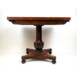 An early Victorian rosewood tea table, the fold over top supported on a swivel action on an